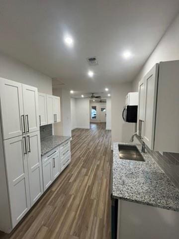 kitchen featuring white cabinetry, dark hardwood / wood-style flooring, ceiling fan, sink, and light stone counters