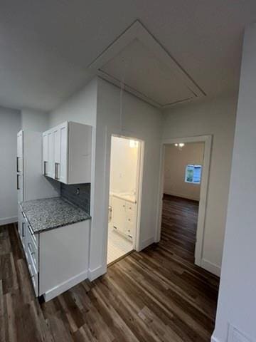 kitchen with dark wood-type flooring, light stone countertops, white cabinetry, and tasteful backsplash