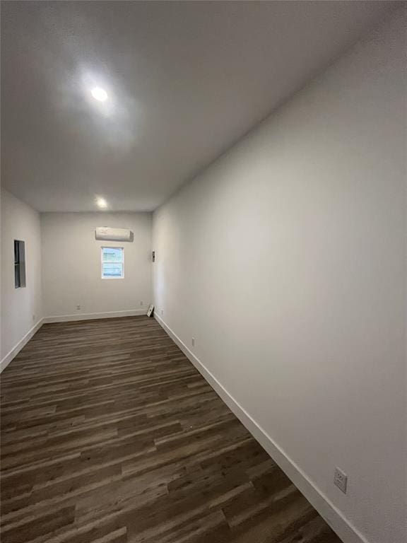 basement featuring dark wood-type flooring and an AC wall unit