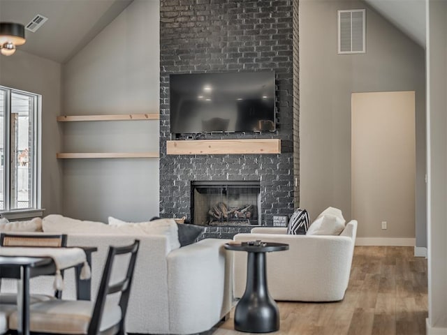 living room featuring a large fireplace, hardwood / wood-style flooring, and vaulted ceiling