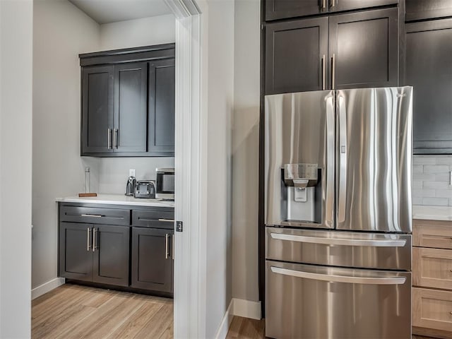 kitchen featuring tasteful backsplash, light brown cabinetry, stainless steel fridge with ice dispenser, and light hardwood / wood-style flooring