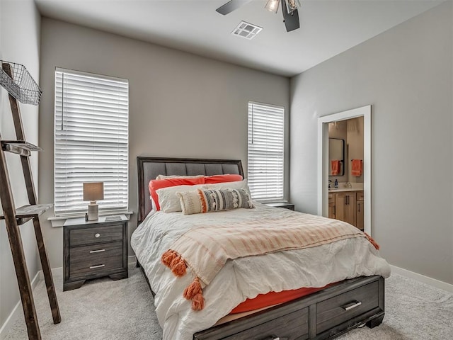 bedroom featuring ceiling fan, ensuite bathroom, light carpet, and sink