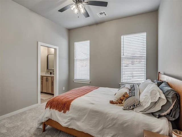 carpeted bedroom with ceiling fan and ensuite bath