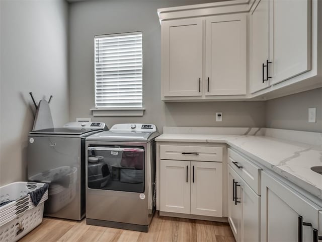 laundry area with washer and clothes dryer, cabinets, and light wood-type flooring