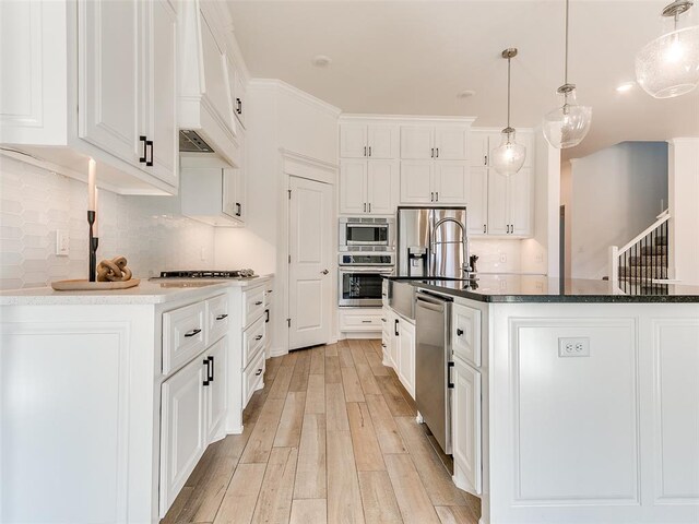 kitchen with white cabinetry, stainless steel appliances, and decorative light fixtures