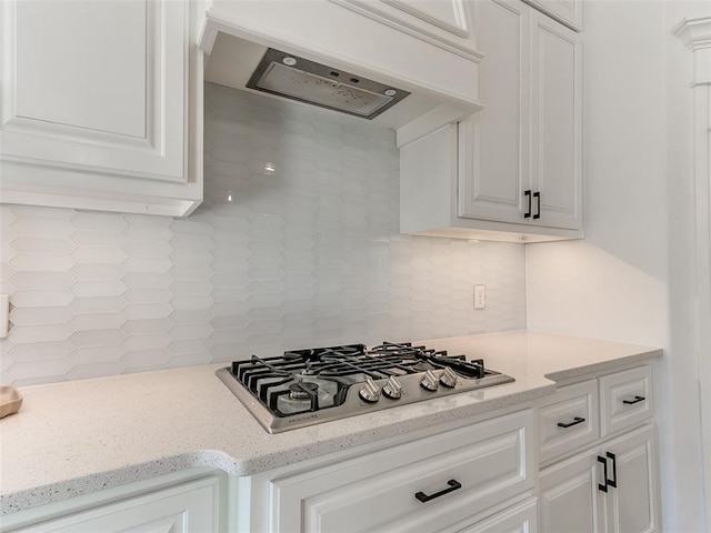 kitchen with premium range hood, white cabinetry, stainless steel gas cooktop, and backsplash