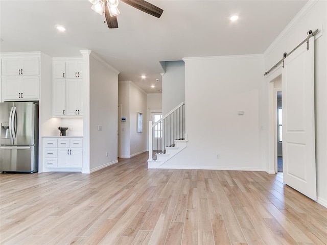 unfurnished living room featuring crown molding, light hardwood / wood-style flooring, ceiling fan, and a barn door