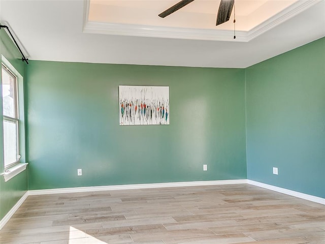 empty room featuring ornamental molding, ceiling fan, light hardwood / wood-style floors, and a raised ceiling