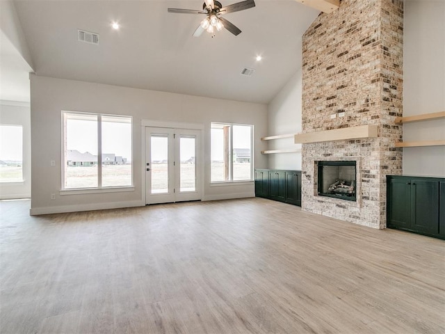 unfurnished living room with beam ceiling, ceiling fan, high vaulted ceiling, a fireplace, and light wood-type flooring