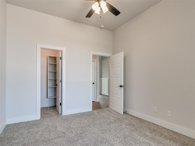 unfurnished bedroom featuring ceiling fan, a spacious closet, light carpet, and a closet