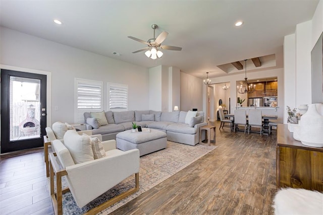 living room with ceiling fan with notable chandelier and dark hardwood / wood-style floors