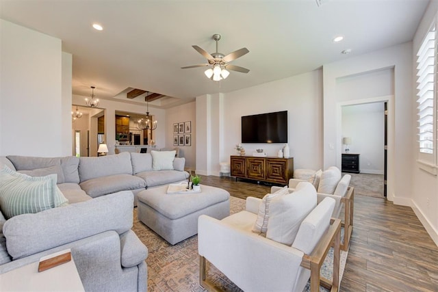 living room featuring wood-type flooring, ceiling fan with notable chandelier, and a healthy amount of sunlight