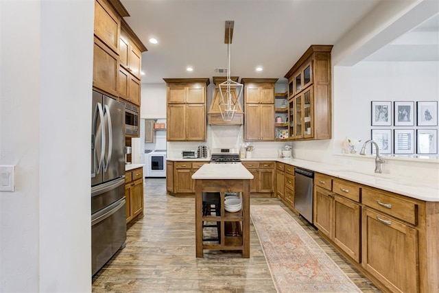 kitchen featuring appliances with stainless steel finishes, premium range hood, sink, a kitchen island, and hanging light fixtures