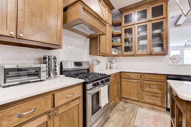 kitchen with backsplash, premium range hood, an inviting chandelier, light hardwood / wood-style floors, and stainless steel appliances