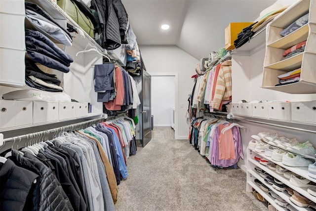 walk in closet with lofted ceiling and light carpet