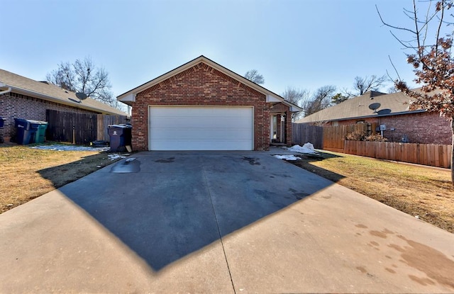garage featuring fence and concrete driveway