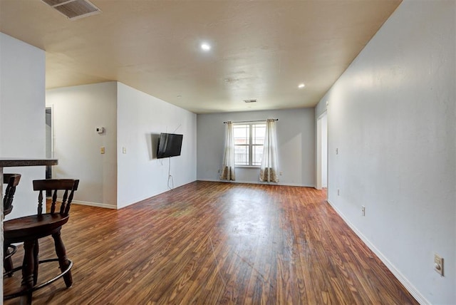 unfurnished living room featuring baseboards, wood finished floors, and visible vents