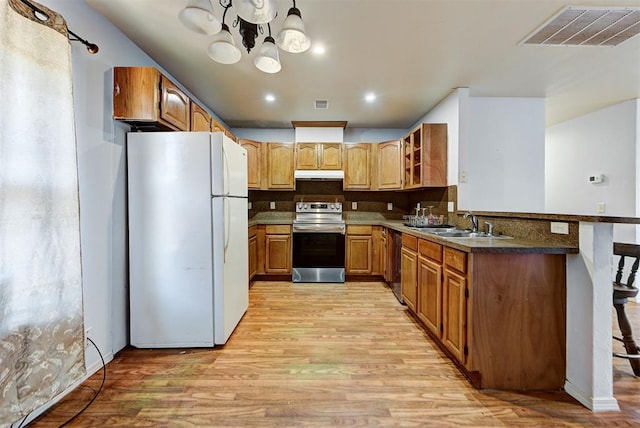 kitchen with stainless steel appliances, visible vents, a sink, and light wood finished floors