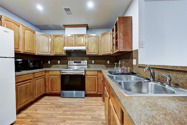 kitchen featuring visible vents, stainless steel range with electric stovetop, a sink, freestanding refrigerator, and under cabinet range hood