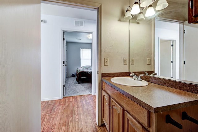 bathroom featuring vanity, baseboards, wood finished floors, and visible vents
