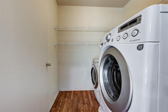 washroom with independent washer and dryer, laundry area, baseboards, and wood finished floors