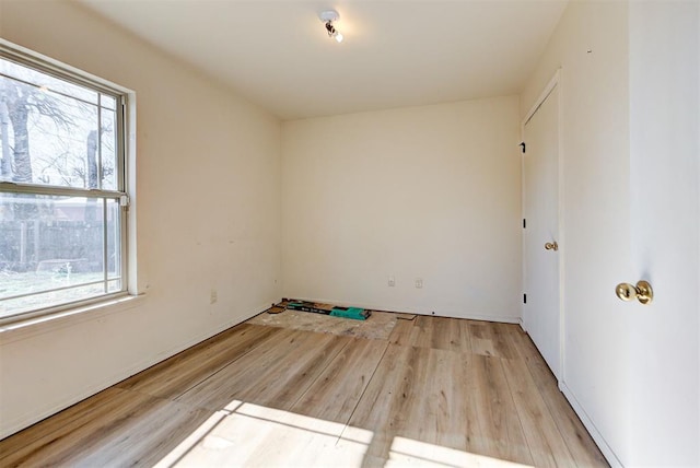 empty room featuring baseboards, a wealth of natural light, and wood finished floors