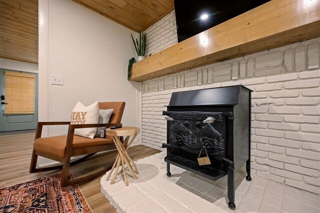 sitting room featuring vaulted ceiling, a wood stove, wood ceiling, and light hardwood / wood-style flooring