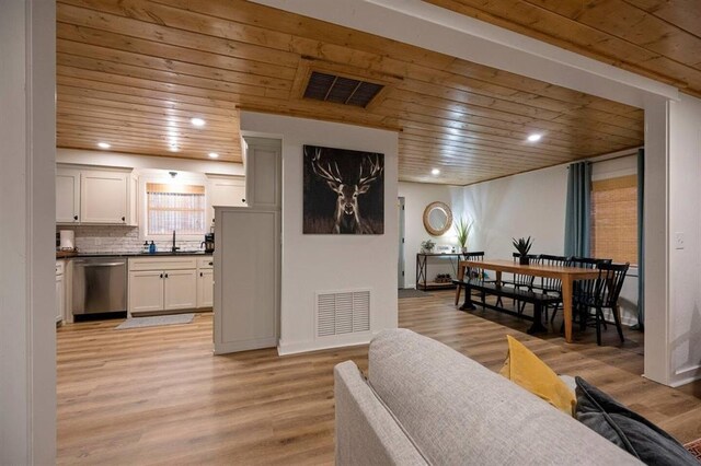 living room featuring light wood-type flooring, wooden ceiling, and sink