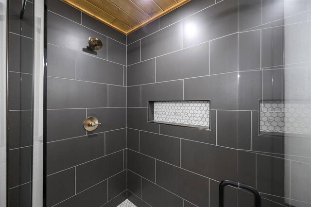 bathroom with a tile shower and wooden ceiling