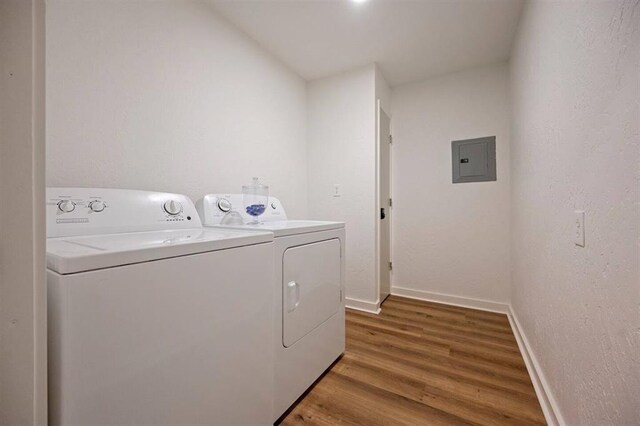 laundry area with hardwood / wood-style floors, electric panel, and washing machine and clothes dryer