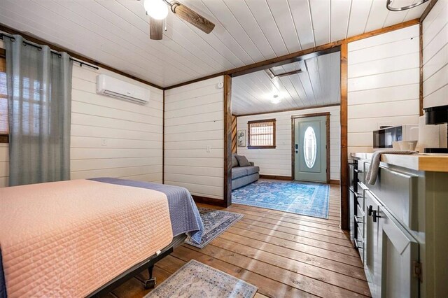 bedroom featuring wooden walls, light hardwood / wood-style flooring, ceiling fan, a wall mounted AC, and wood ceiling