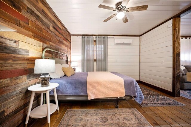 bedroom featuring dark hardwood / wood-style floors, a wall mounted AC, wooden walls, and ceiling fan