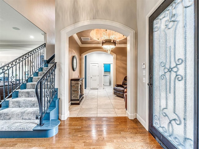 foyer with a notable chandelier, ornamental molding, and hardwood / wood-style floors