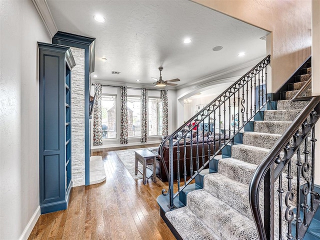 entryway featuring ceiling fan, wood-type flooring, and ornamental molding