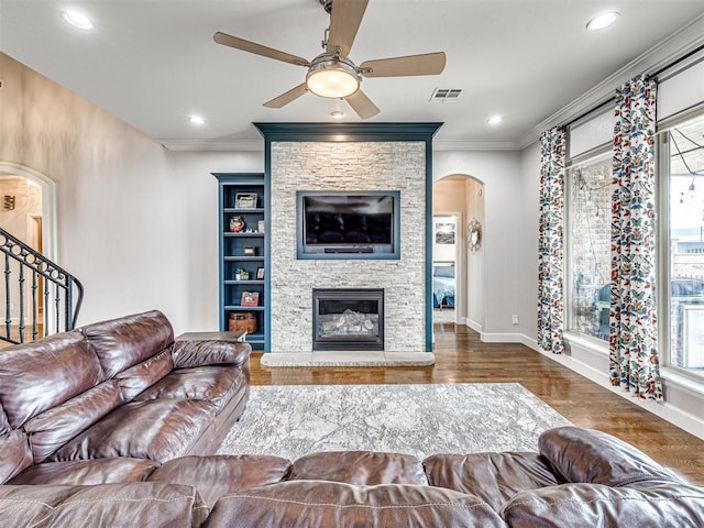 living room featuring ceiling fan, dark hardwood / wood-style flooring, ornamental molding, and a fireplace