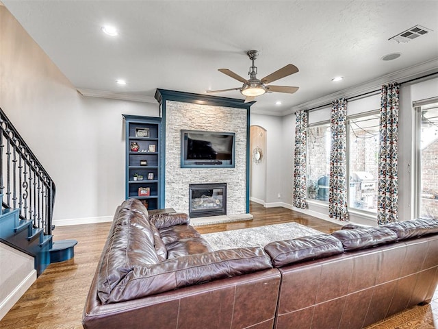 living room with ceiling fan, hardwood / wood-style floors, ornamental molding, and a fireplace