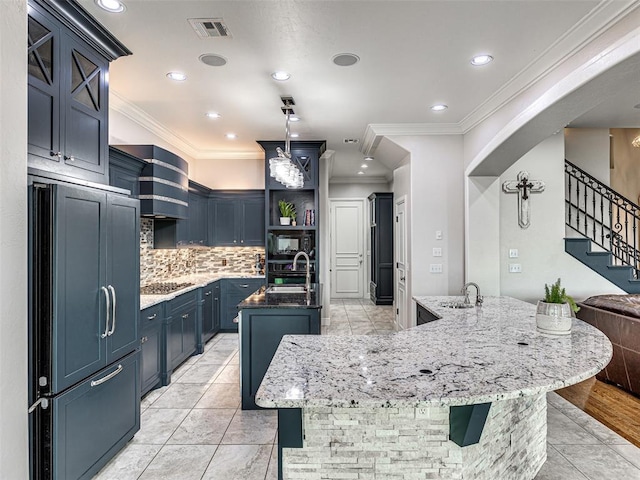 kitchen with black appliances, blue cabinetry, a center island with sink, and sink