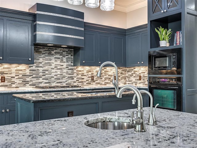 kitchen featuring sink, blue cabinetry, light stone countertops, black appliances, and decorative backsplash