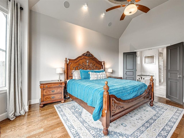 bedroom featuring vaulted ceiling, ceiling fan, light hardwood / wood-style flooring, and multiple windows