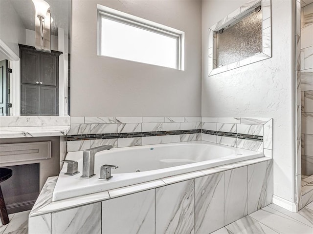 bathroom with tiled tub and vanity