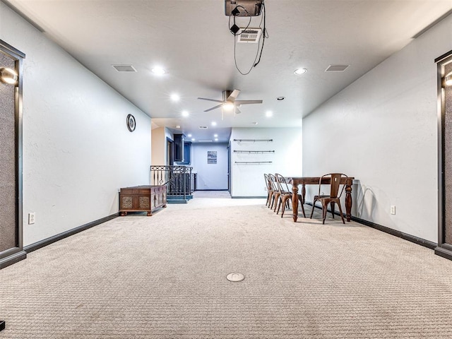 sitting room with ceiling fan, light colored carpet, and indoor bar