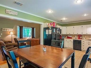 kitchen featuring decorative backsplash, white cabinets, black appliances, and ornamental molding