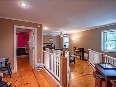 corridor with a wealth of natural light, ornamental molding, and light wood-type flooring