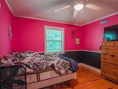 bedroom featuring hardwood / wood-style flooring, ceiling fan, and crown molding