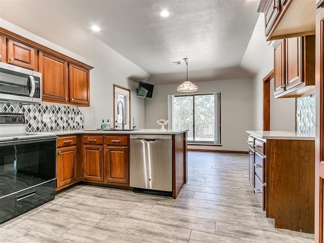 kitchen with sink, stainless steel appliances, tasteful backsplash, kitchen peninsula, and pendant lighting