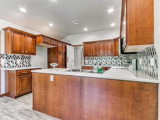 kitchen with kitchen peninsula, range, light hardwood / wood-style flooring, and sink