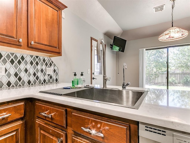 kitchen with backsplash, dishwashing machine, sink, and decorative light fixtures