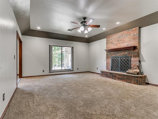 unfurnished living room featuring a textured ceiling, ceiling fan, carpet floors, and a fireplace