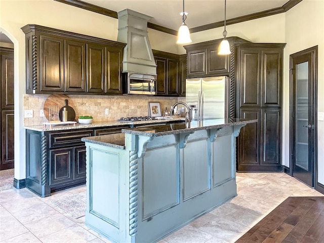 kitchen with appliances with stainless steel finishes, a center island with sink, and dark stone countertops