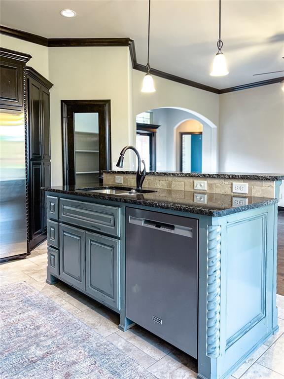 kitchen featuring sink, stainless steel appliances, crown molding, pendant lighting, and a kitchen island with sink